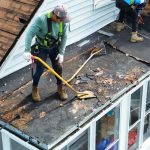 Professional roof replacement in progress with contractors removing old shingles on a residential home