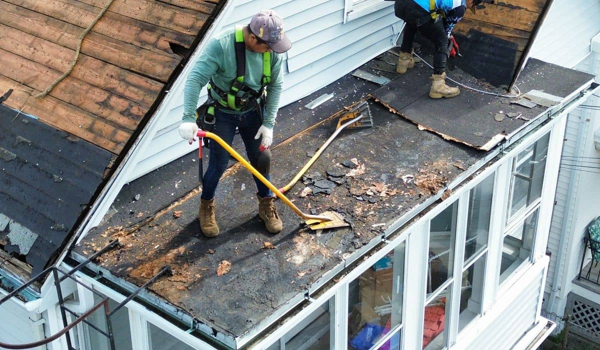 Professional roof replacement in progress with contractors removing old shingles on a residential home