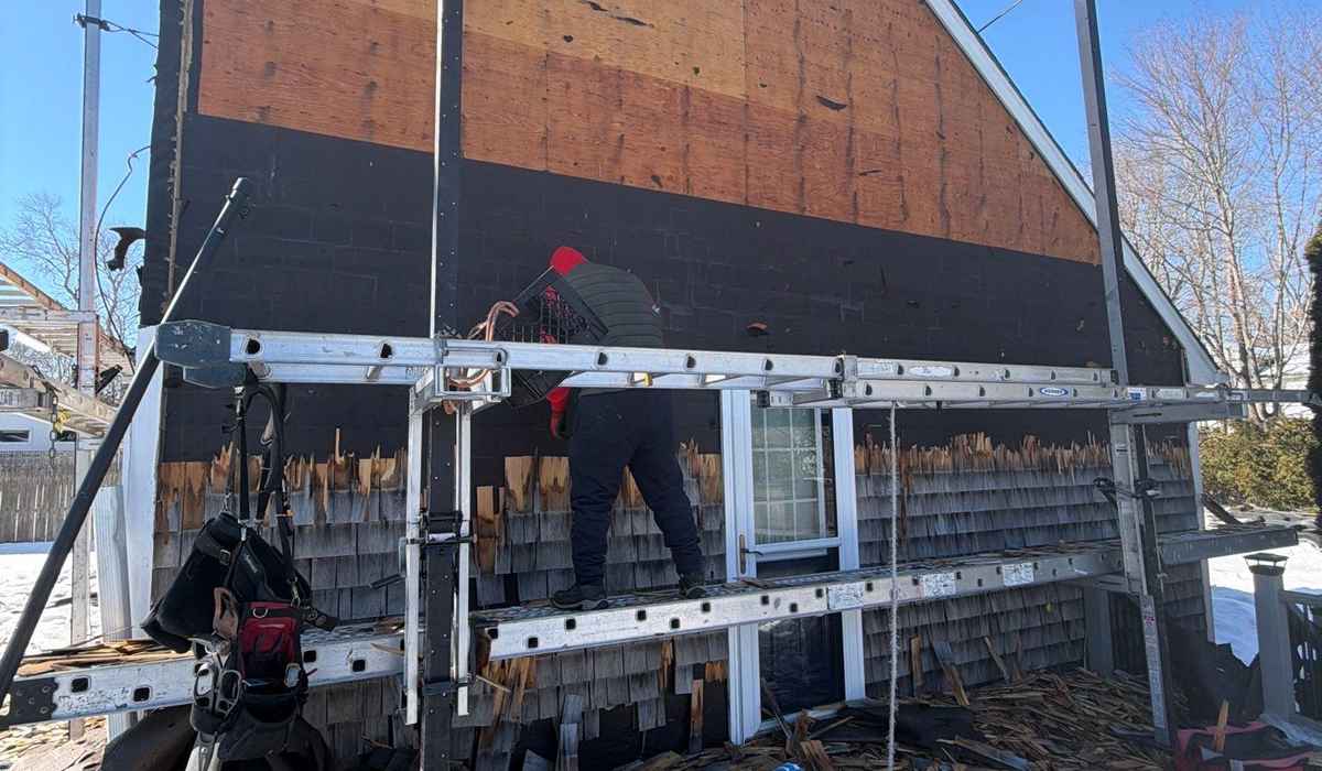 roof leak repair guide common causes solutions homeowners Professional contractor repairing exterior wall damage caused by roof leak during home restoration